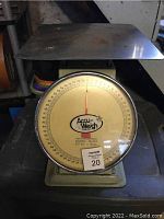 Wide view of the vintage scale showing metal weighing platform and front dial with Accu-Weigh logo, model M-64, and capacity information.