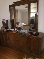Full front view of vintage dresser with large attached mirror, displaying scratches and items on top.