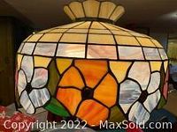 Close-up of lamp shade showing stained glass floral pattern with amber, white, and pink petals.