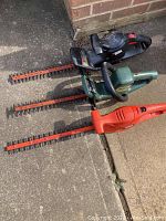 Three Black & Decker hedge trimmers laid side by side showing blades and handles.
