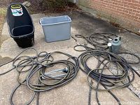 Overview photo showing two black garden hoses (one with metal sprinkler attachment), gray plastic watering can, gray plastic tub, and Easy GO XL garden cart on concrete.