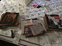 Vintage Life magazines stacked in a pile alongside Sun newspapers and Sun magazines on a mattress.