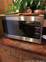 Front angled view of the Panasonic NN-SD986S microwave showing stainless steel body, glass door, and countertop placement