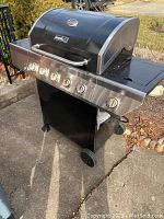 Full view of Nexgrill gas grill on concrete showing hood, control panel, cabinet, and wheels.