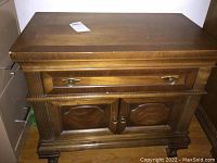 Photo showing front of one wooden nightstand with drawer, cabinet doors, and brass hardware.