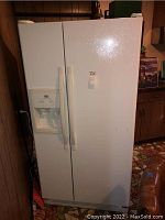 Full view of white side-by-side refrigerator with water and ice dispenser on left door and handles on both doors.