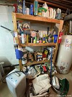 Wide view showing GE dehumidifier unit on floor near wooden shelving with various household and chemical products