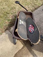 Metal wagon on wheels with two skateboards inside, showing weathered condition