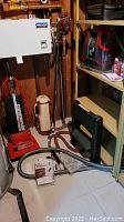 Three vacuum and carpet cleaners together including Kenmore commercial vacuum (beige), Electrolux upright vacuum (red) and Hoover Spotless portable carpet cleaner with hose attached on floor.