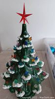 Front view of assembled ceramic tree with snow accents, plastic bulbs and red star topper