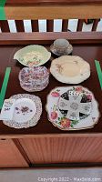 Top view of assorted china plates, teacup, saucer, and dishes laid on table showing various floral patterns and shapes.