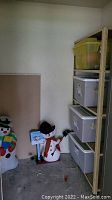 Metal shelving unit with four plastic storage totes placed on each shelf, two inflatable snowman lawn decorations standing next to the shelf.