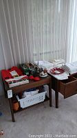 Wide view of tables with assorted Christmas decorations including textiles, boxes, and figurines