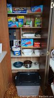Shelf of assorted kitchen storage bags including Ziploc, Reynolds Wrap, wax paper, and Glad plastic wrap, and various kitchen containers placed on shelves and floor.
