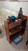 Wooden bookshelf set against a white leather couch with glass fishing balls, ship-themed bookends, various tiles, books, and blue box on shelves