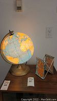 Wide shot of the illuminated vintage globe lamp and Aloha decorative item on a wooden surface, showing placement and general condition.