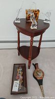 Full view of heart shaped table with three clear glass birds, amber spotted glass purse, two framed art pieces on floor