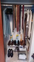Closet view showing men's belts hanging, Levi's denim shirt, sweaters, shoes on shelf, and socks below