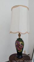 Full view of lamp with white pleated shade and floral ceramic base