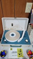 General Electric portable record player in white/blue open case showing turntable, tonearm, and control knob