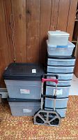 Wide view of plastic storage totes, storage tower and metal dolly with telescoping handle