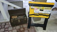 Toolbox open with assorted tools alongside collapsed sawhorse