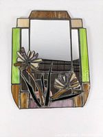 Full view of rectangular wall mirror framed by multicolored stained glass with 3D floral elements.
