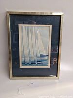 Full view of framed print showing gold-toned frame and mat board surrounding the sailboat art print.