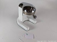 Front and side view of the manual citrus juicer showing the white base and chrome pressing dome.