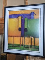 Full view of framed 'Square Dog' print showing three stylized dogs in purple, green, yellow on gold background