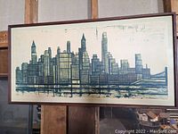 Full front view of framed cityscape print hanging against wooden supports