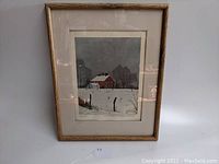 Framed limited edition print of a red house in a snowy field by Leland McClelland on a white background with a visible tag labeled '27'.