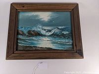 Front view of framed oil painting showing moonlight surf with waves and rocks, and signature visible.