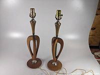 Pair of mid century wood table lamps with open heart-shaped bases and round bases on a white background.