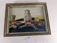 Front view of the framed oil painting showing the full still life scene with fruits, stoneware, and a brass pitcher, highlighting the signature of E. Sutherland.