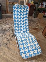Full view of the chaise lounge chair with blue and white patterned fabric cover showing its shape and design on a wooden floor.