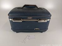 Closed blue vintage American Tourister Tiara Line travel case with metal clasps and handle, showing front and top.