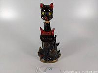 Front view of vintage black cat whiskey decanter with detailed features and label
