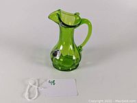 Green translucent glass pitcher with handle and original Kanawha Glass label visible on the side, showing overall shape and design.
