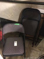 Close-up of folding metal chair with patterned fabric seat and backrest, showing detail of upholstery pattern and metal frame.