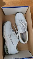 Pair of white Nike ladies golf shoes size 8 inside their box, showing overall condition and styling.