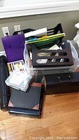 Wide view of a collection of office supplies including binders, desk organizers, folders, and a storage bin