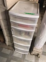 Angle view of the whole 6 drawer plastic organizer in a basement area showing the front and side of the unit.