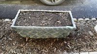 Side view of a cemented rectangular planter showing lattice pattern and filled with soil.