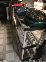 Side perspective showing three connected sections of beige plastic utility shelving unit with some stored items on top shelves.