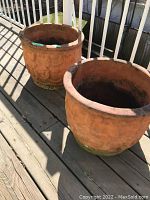 Two terracotta plant pots displayed on an outdoor wooden balcony floor, showing overall shape and size.