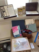 Photo showing calligraphy kit, pens, nibs, practice pad, two U Film slide kits, scrapbook, binoculars with leather case, and miscellaneous items on floor