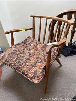 Front view of the wooden chair with paisley-patterned cushion in place