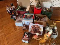 Wide view of lot showing nutcrackers, boxed items, wooden figurines, and holiday decorations on floor