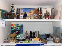 Shelf showing various international collectibles including Queens Guard figurines, street clock model, prints, and assorted small souvenirs.